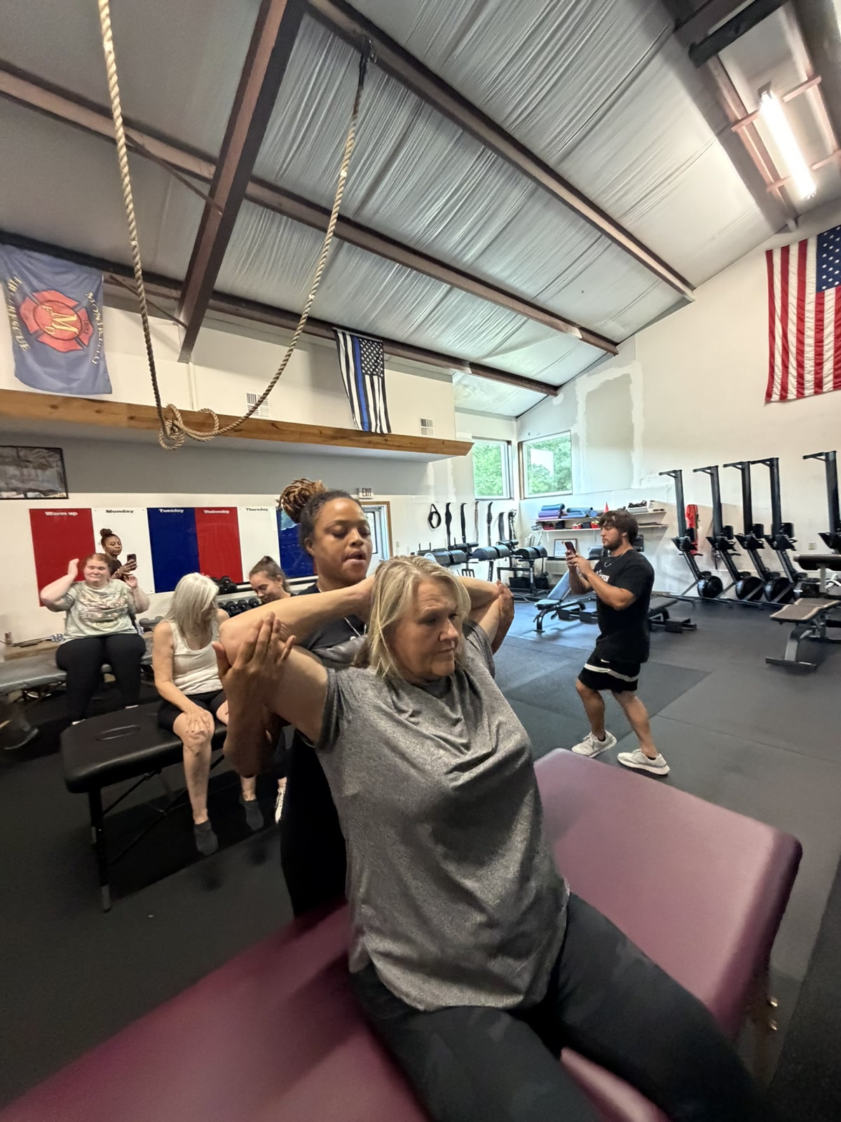 A client receiving an upper-body stretch in a group session